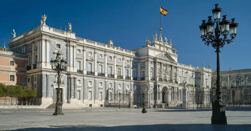 Royal Palace of Madrid main facade with royal standard flag flying, viewed from the courtyard