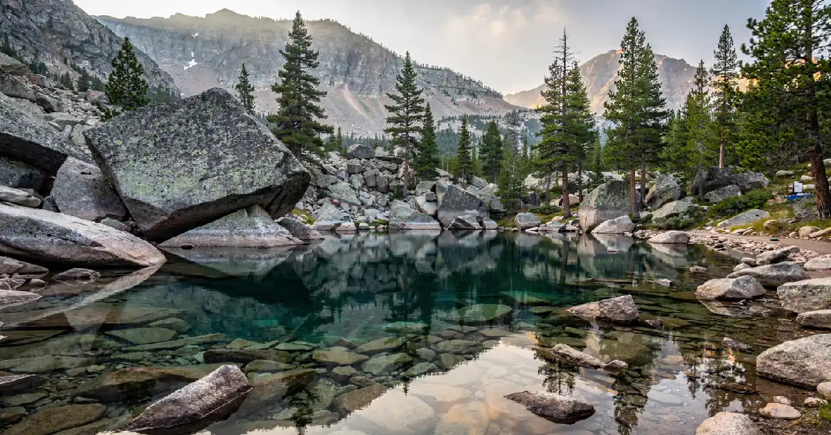 Gem Lake granite pool surrounded by boulders and pine trees on a hidden trail in Rocky Mountain National Park