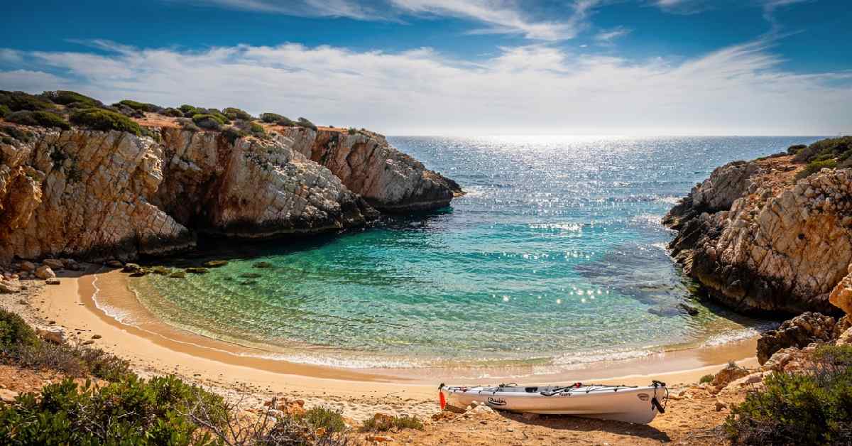 Curved sandy cove framed by cliffs and turquoise water at Sovareto beach near Sciacca Sicily.