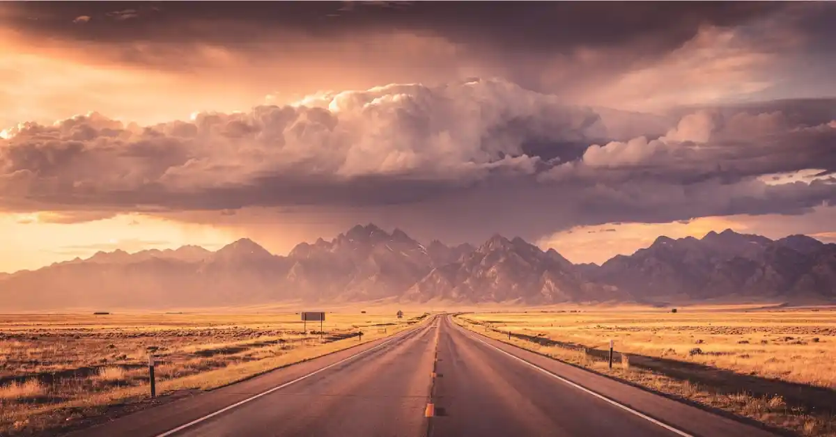 wyoming road trip empty highway open plains mountains dramatic sky